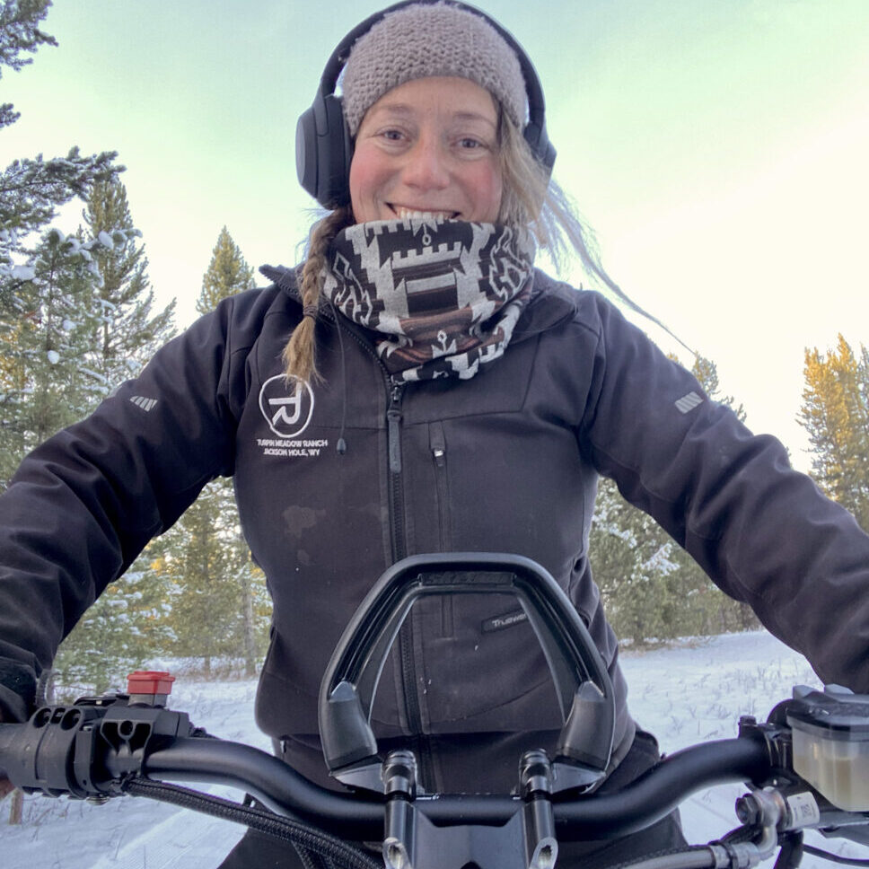 Elee sitting on her snowmachine with a big smile